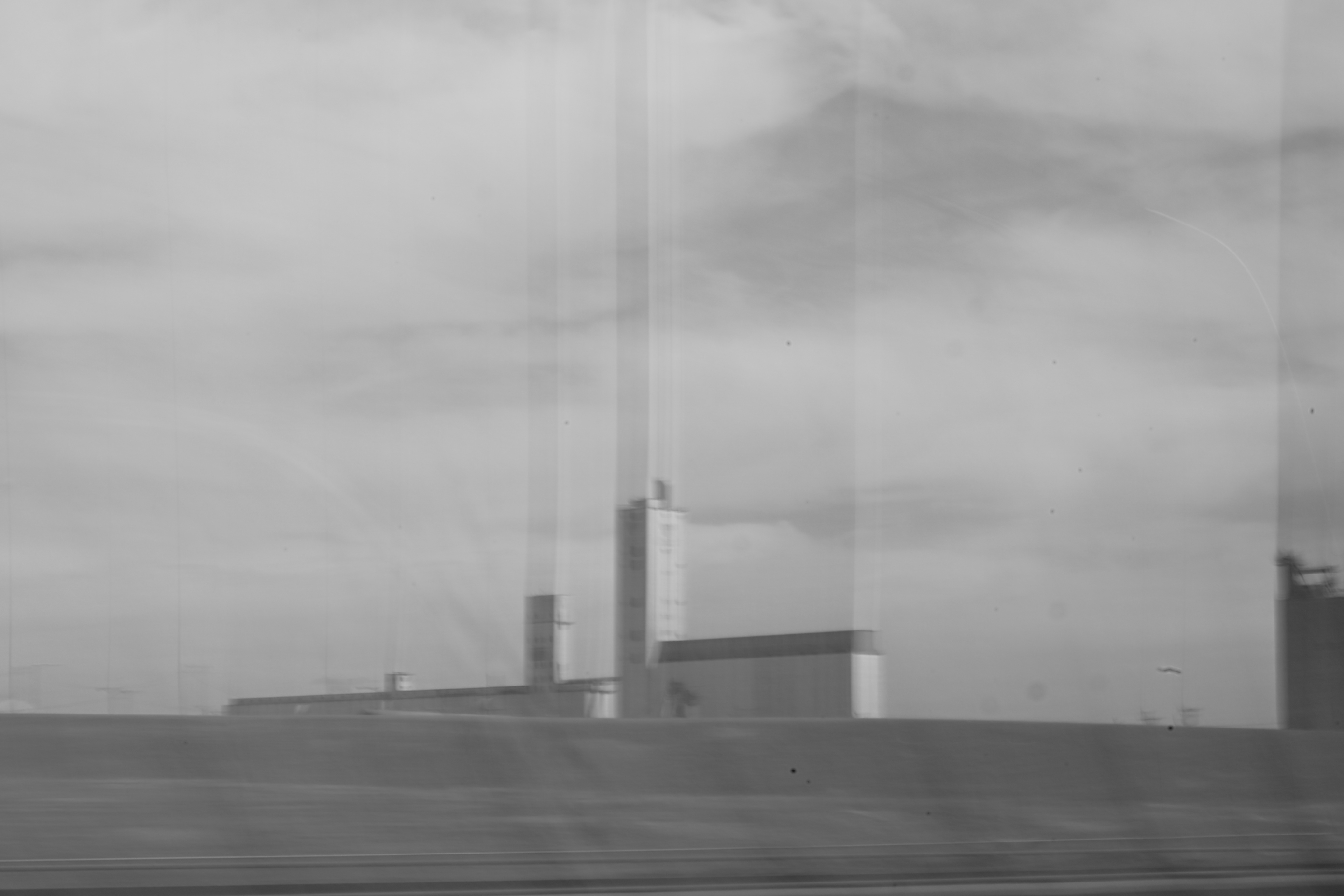blurry black and white photo of a grainery, with the towers extending through blurred streaks to the top of the frame